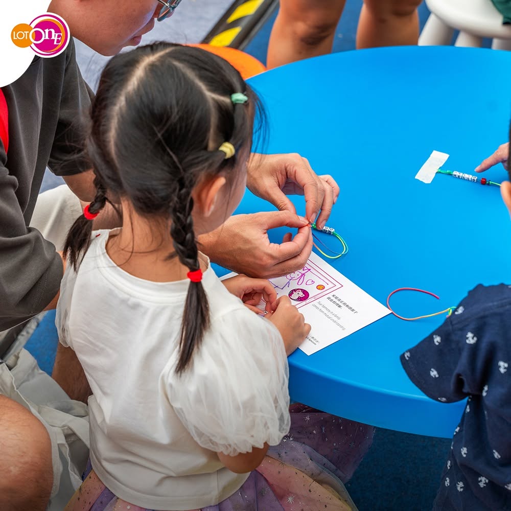 Children making bead crafts at a guided activity table at Lot One