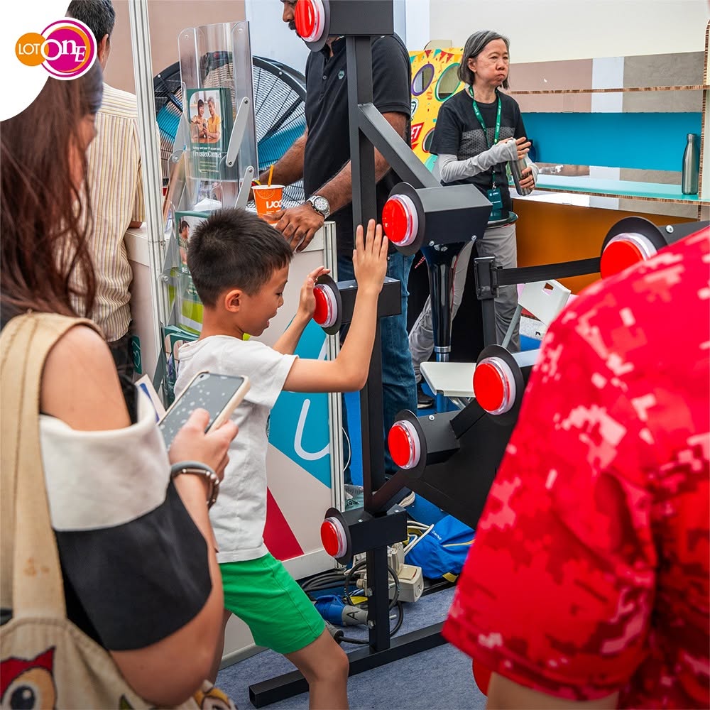 Child playing an interactive red-button game at Lot One