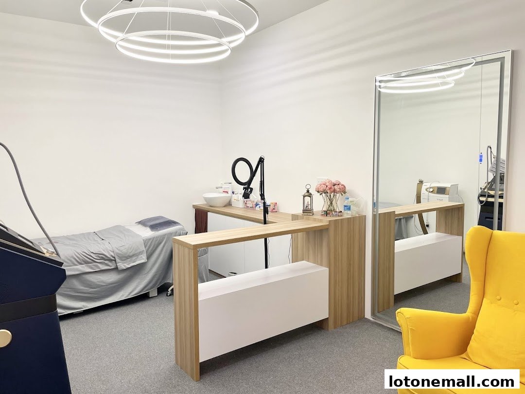 Interior of an aesthetics clinic with a treatment bed, reception desk, and a yellow armchair.