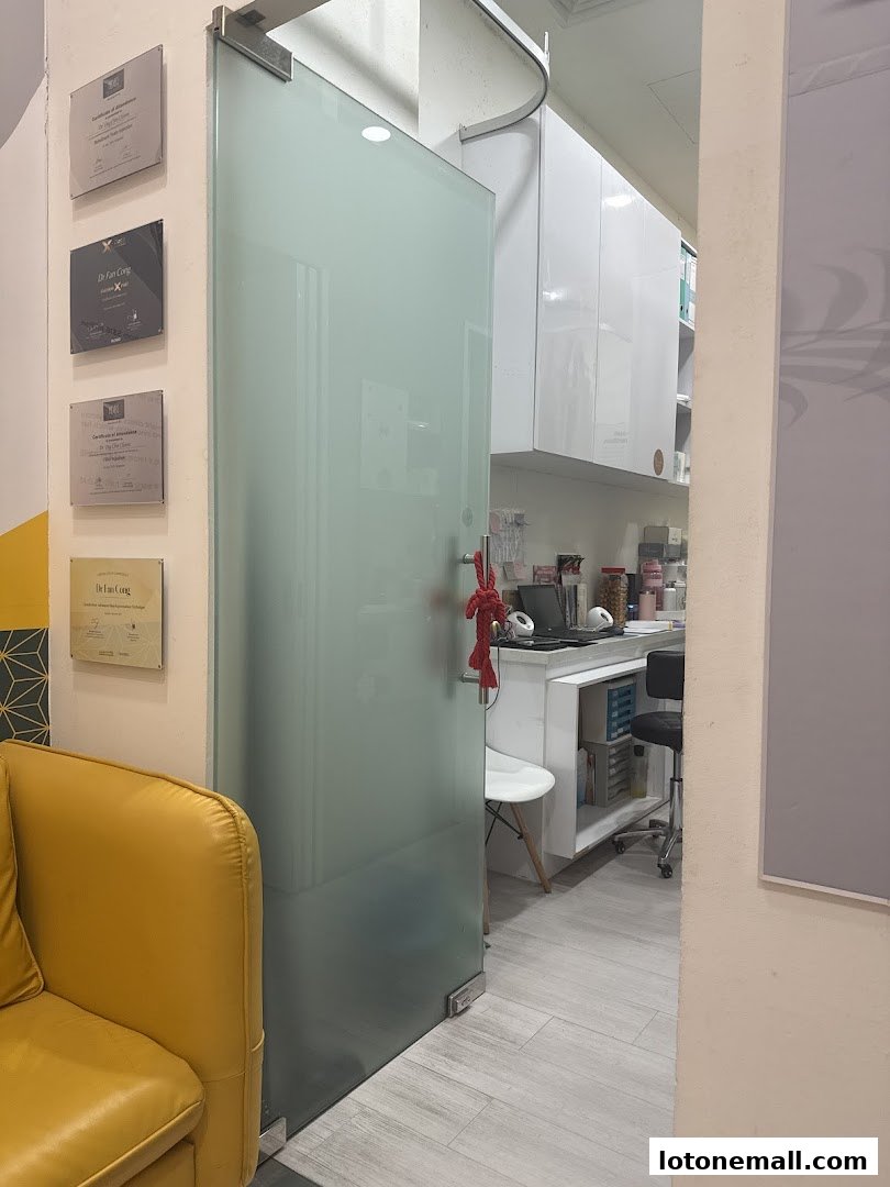 Interior view of A.M Aesthetics Lot1, showing a frosted glass door, certificates on the wall, and a reception area.