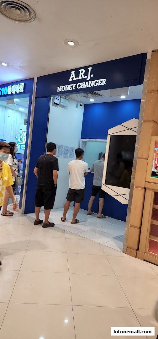 People queuing at A.R.J. Money Changer shop with blue interior and signage.