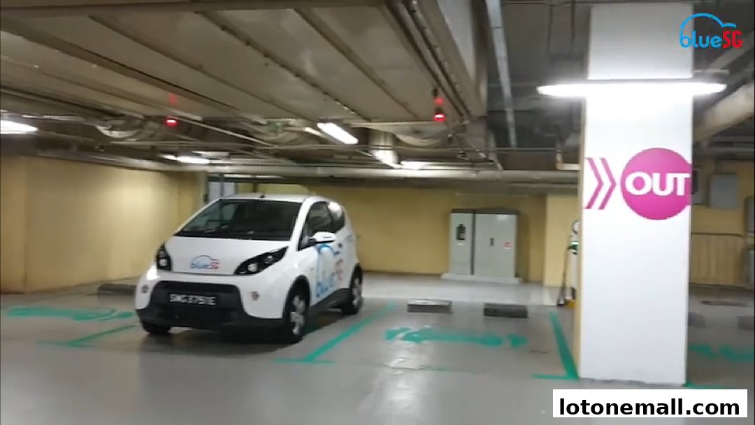 A white electric car from BlueSG parked in a parking lot with an 'OUT' sign.