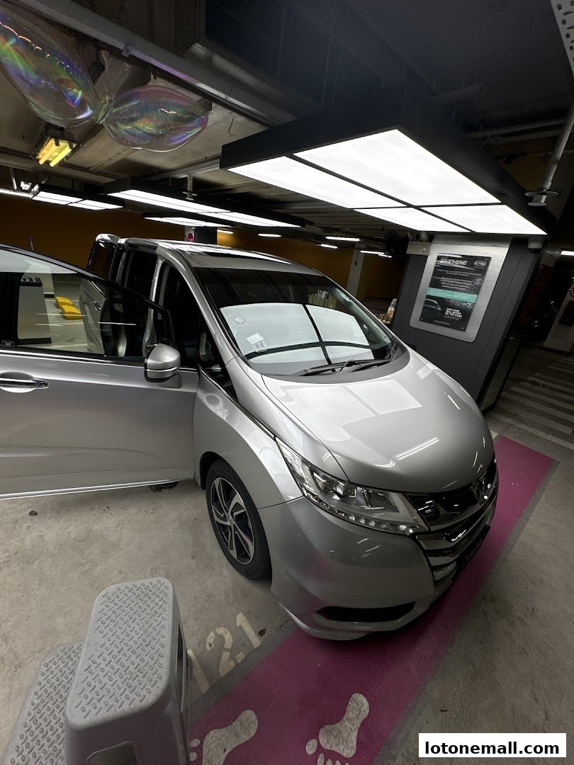 A silver car with its doors open is parked in a brightly lit garage.