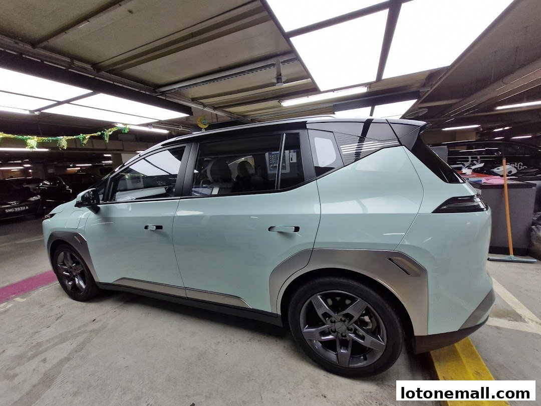 A light blue electric car parked in a garage with bright overhead lighting.