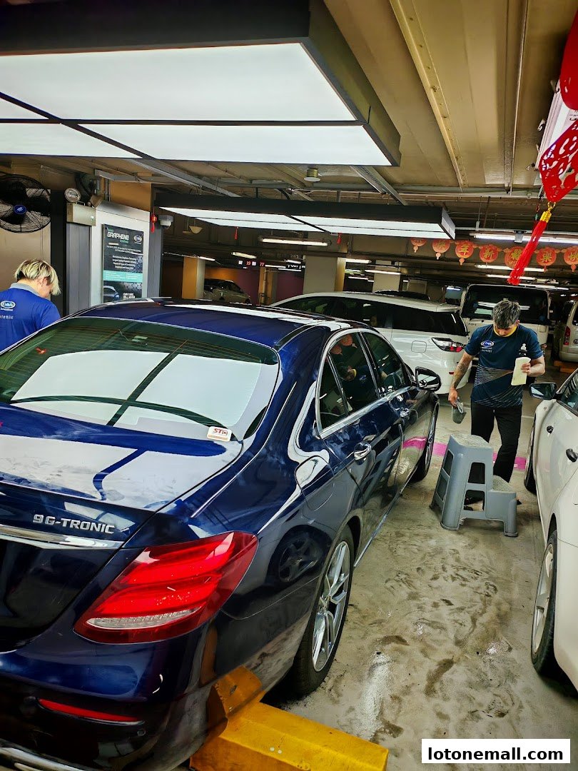 Car detailing service in progress with staff working on a blue sedan.