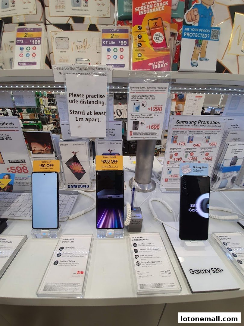 A display of Samsung smartphones and promotions in a retail store, with social distancing signs.