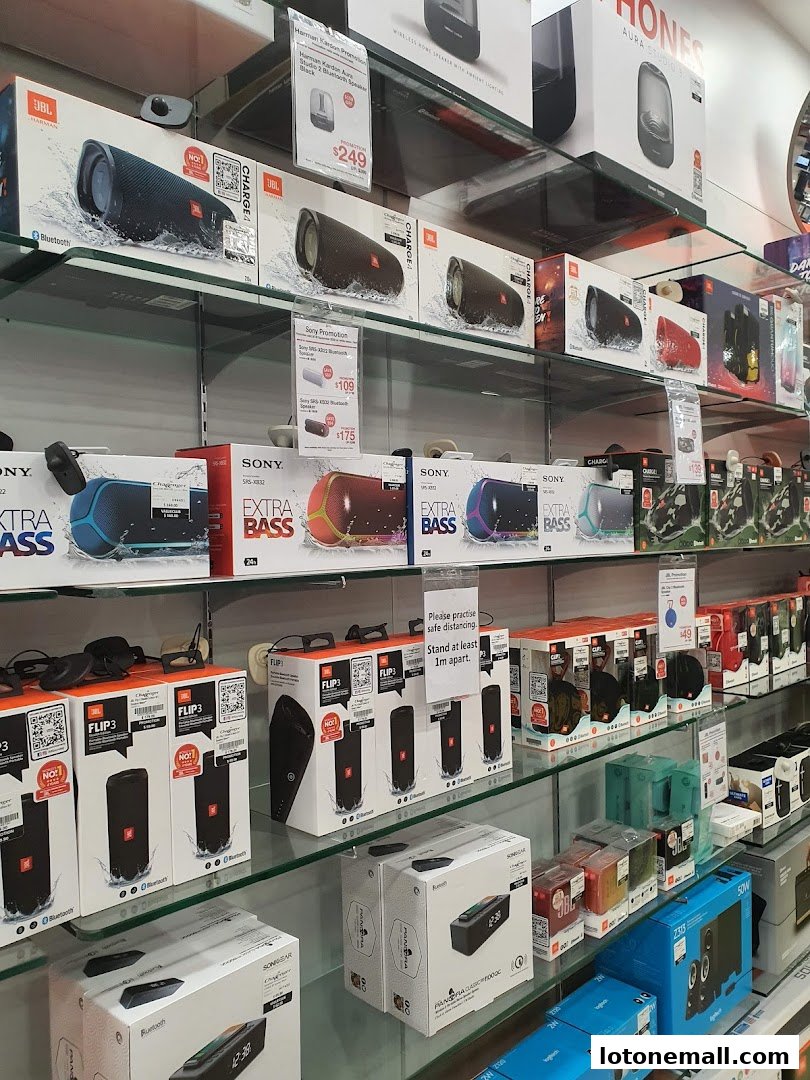 Shelves filled with various portable Bluetooth speakers and audio devices from brands like JBL and Sony.