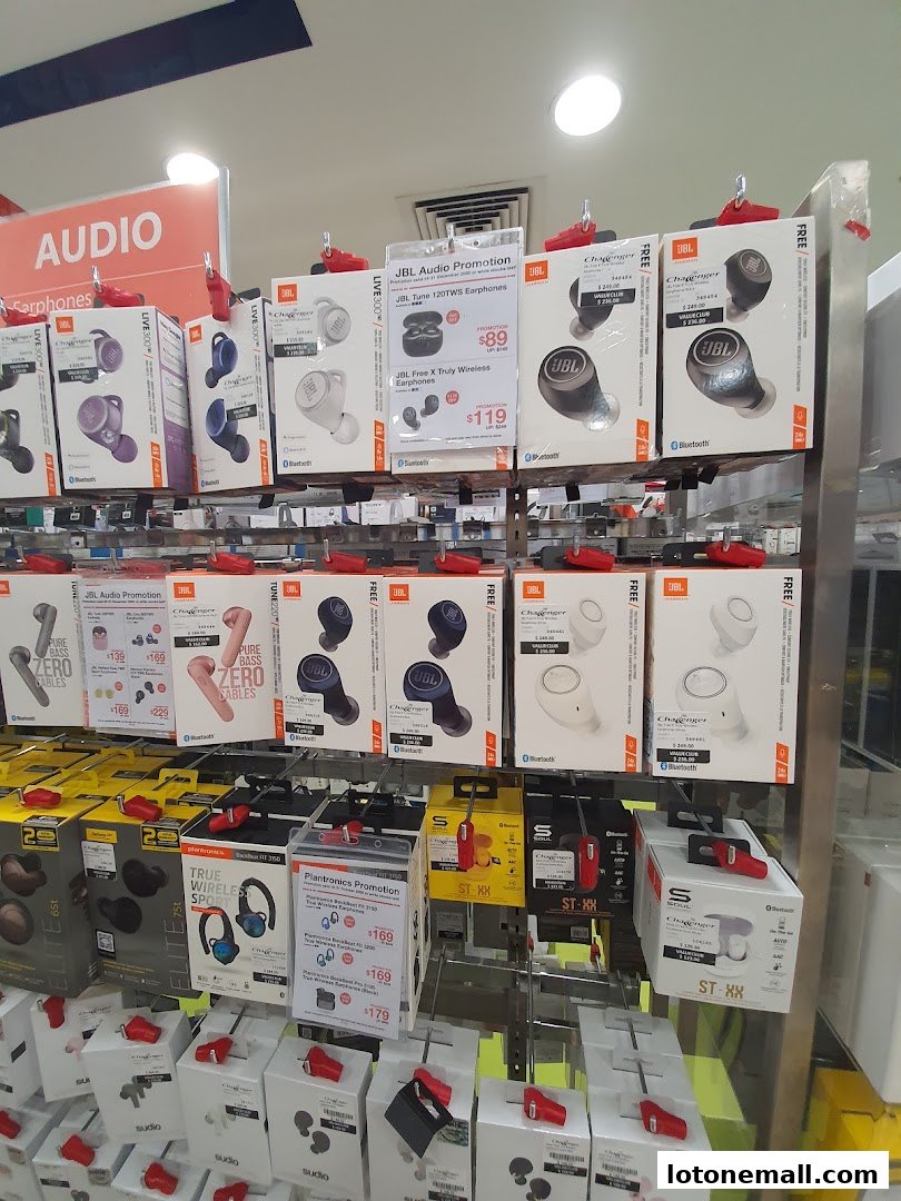 A display of various wireless earphones and audio accessories from brands like JBL and Plantronics.