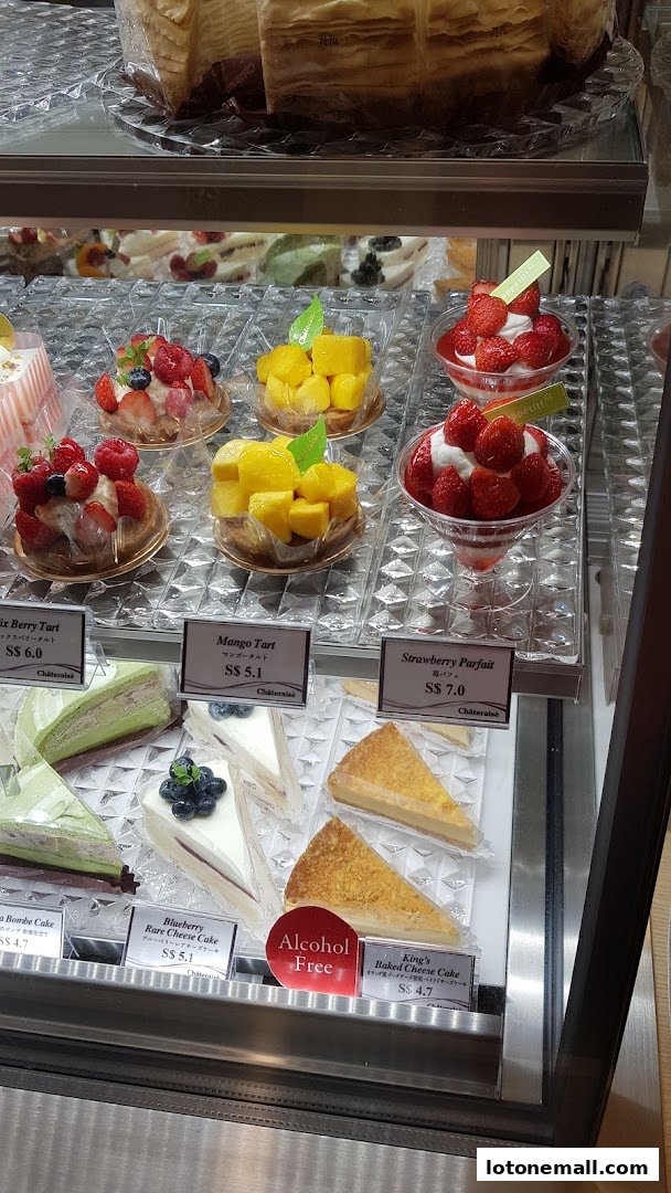 A display case filled with various colorful cakes and desserts, including tarts and parfaits.