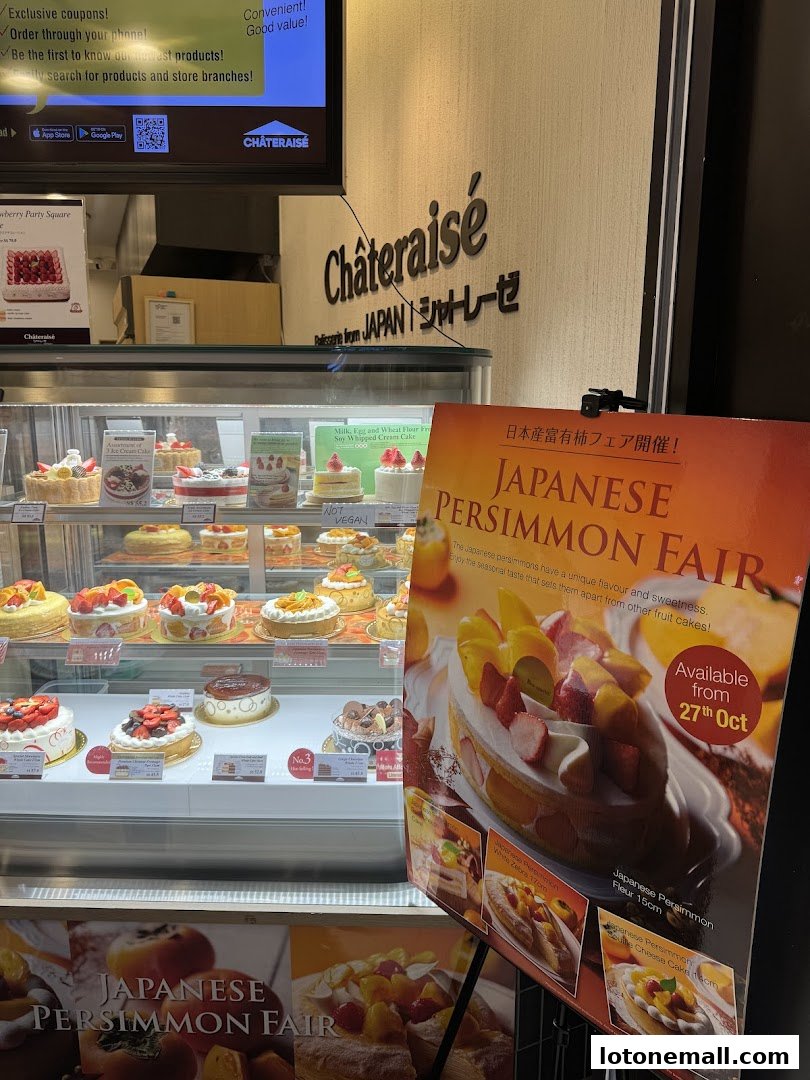 A display of various cakes and pastries at Châteraisé, with a promotional poster for a Japanese Persimmon Fair.
