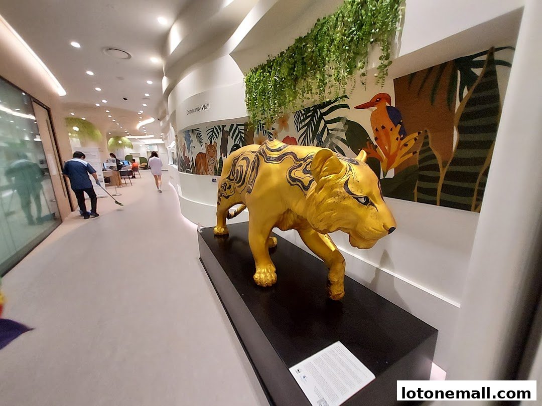 A golden tiger statue is displayed in a modern library with a community wall and greenery.