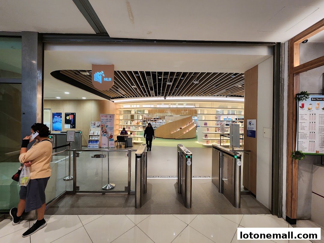 Entrance to a modern public library with turnstiles and a view of the interior.