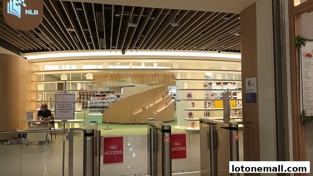 Interior view of a modern public library with bookshelves, seating areas, and an entrance gate.