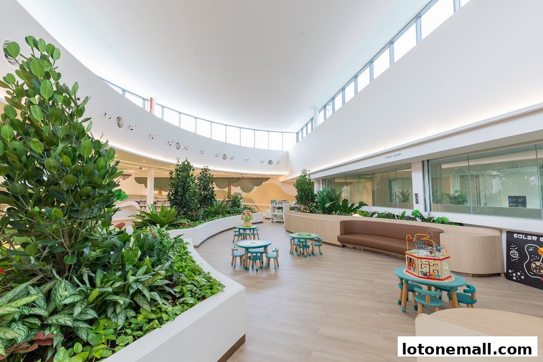 Interior of a modern library with lush greenery, children's play area, and seating.