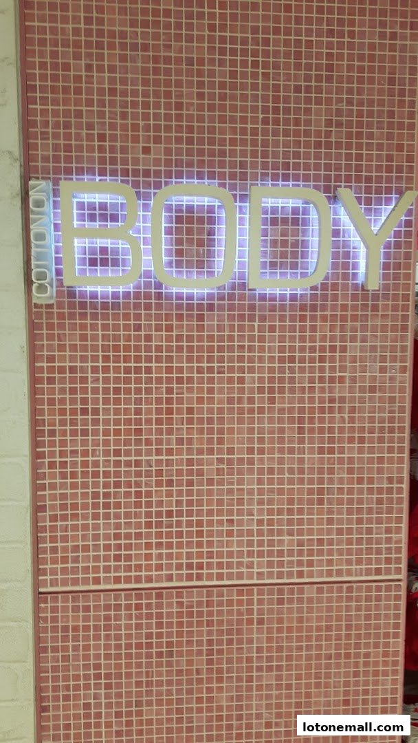 A close-up of the Cotton On Body store sign with pink tiled walls.