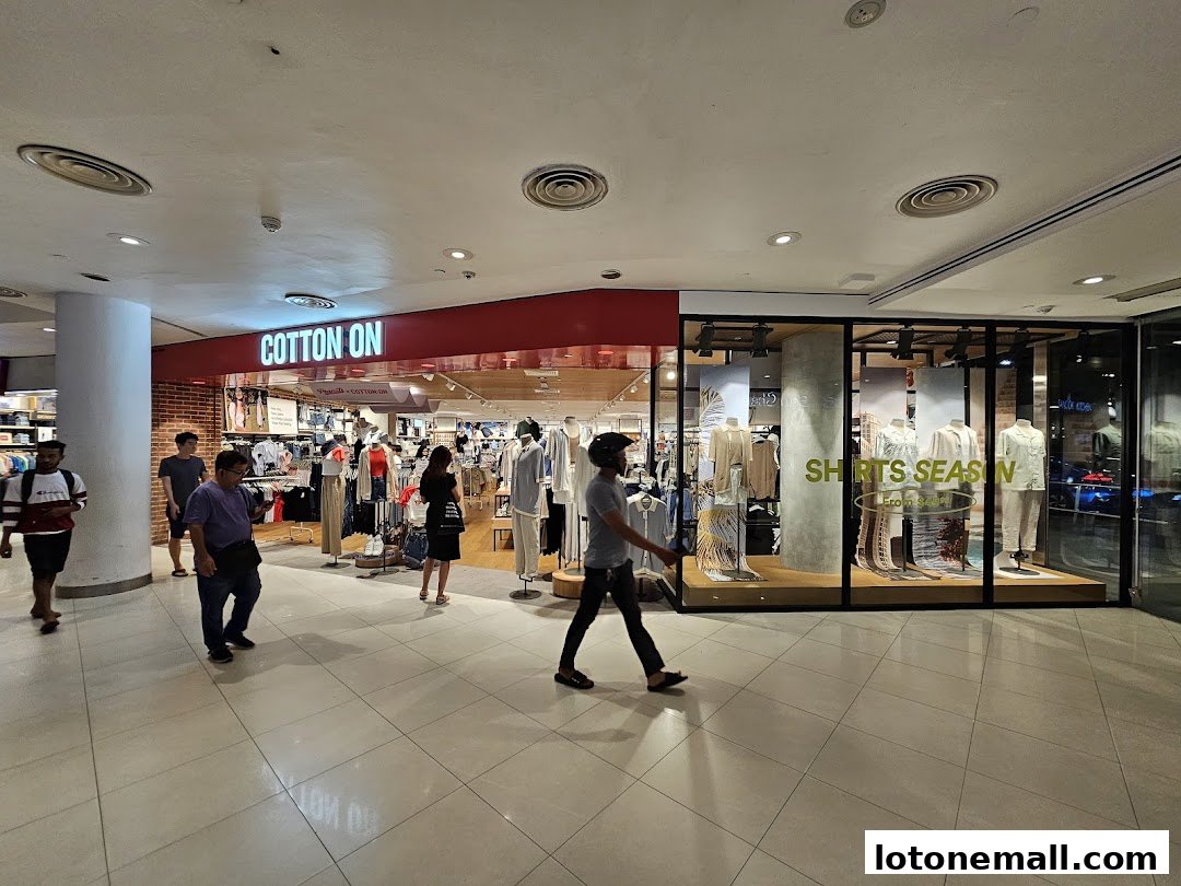 The Cotton On store entrance with mannequins displaying shirts and people walking by.