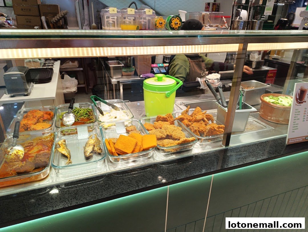 A display of various prepared dishes, including fried chicken and fish, at a food counter.
