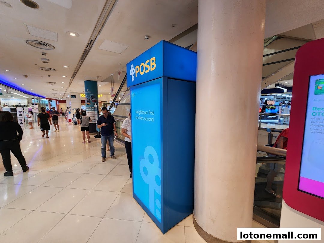 A POSB ATM kiosk is located in a busy shopping mall with people walking by.