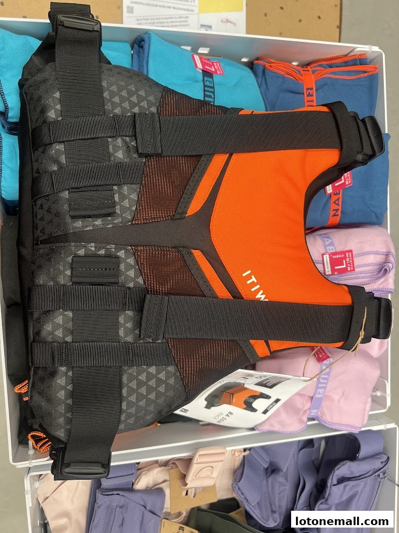 A close-up of a black and orange life vest displayed with folded clothing items.
