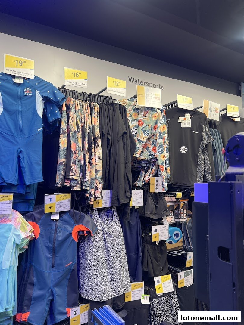 A display of watersports apparel including wetsuits, rash guards, and swimwear.