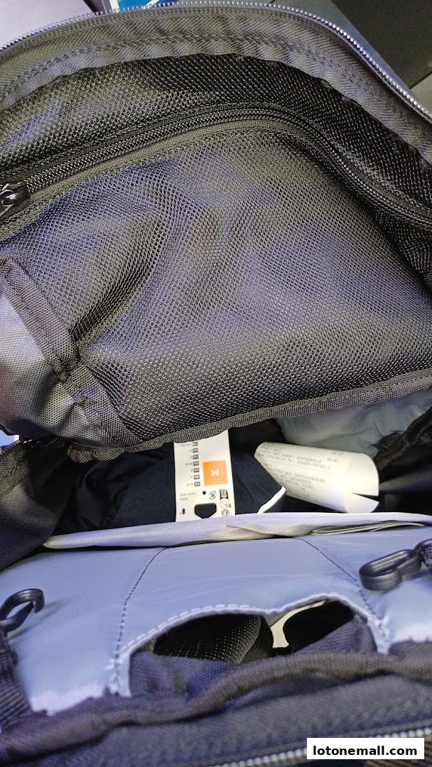 Inside view of a black backpack with mesh compartments and clothing tags.