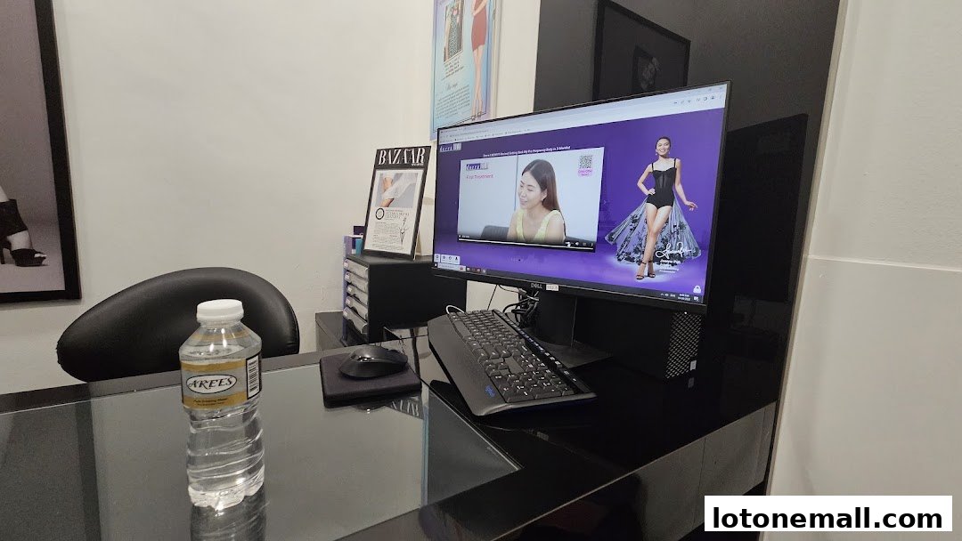 A desk with a computer displaying a slimming treatment video and a bottle of water.