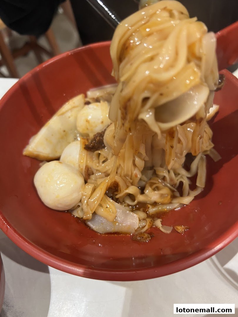 A close-up shot of a bowl of noodles with fish balls and other ingredients.