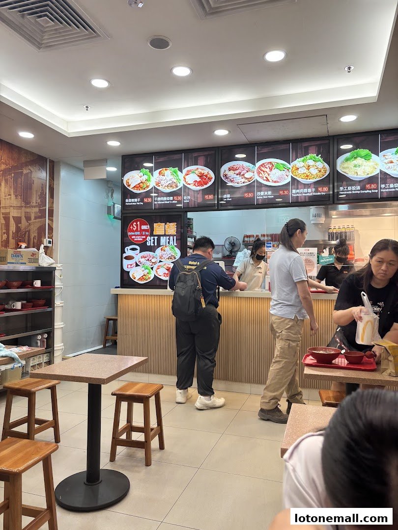 Customers ordering food at a counter with a menu display above.