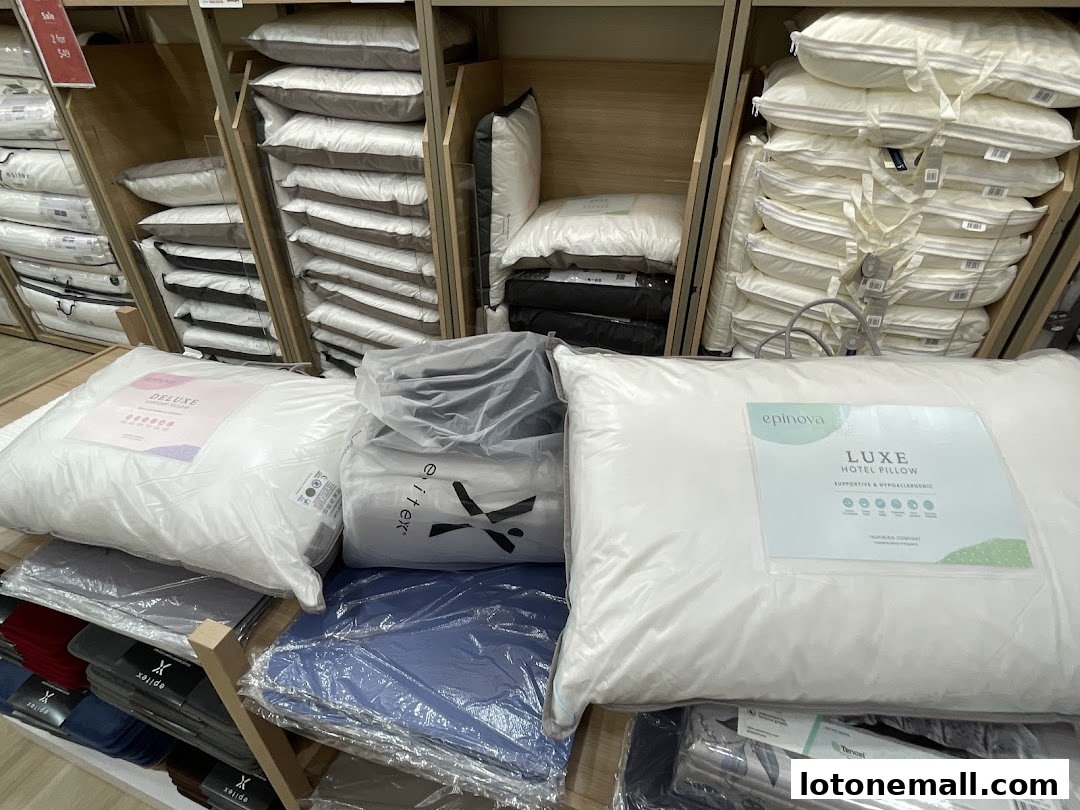 A display of various pillows and bedding products, including 'Deluxe' and 'Luxe Hotel Pillow' options.