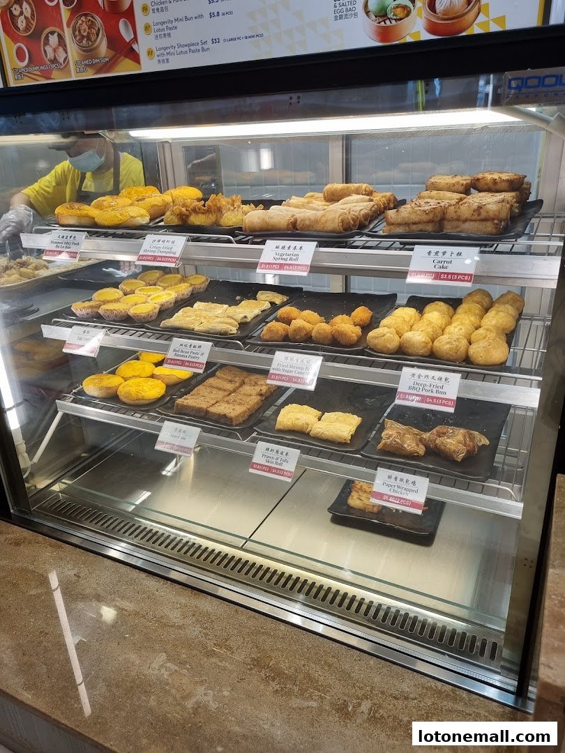 A display case filled with various dim sum items, including buns, pastries, and fried snacks.