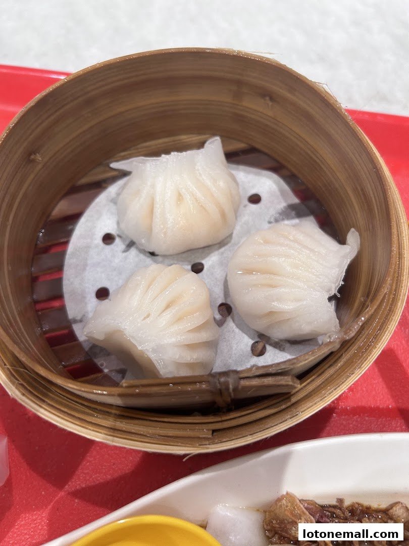 A close-up of three delicate steamed dumplings in a bamboo steamer basket.