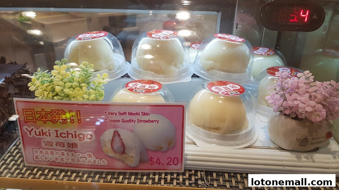 A display of individually packaged mochi desserts with a strawberry filling.