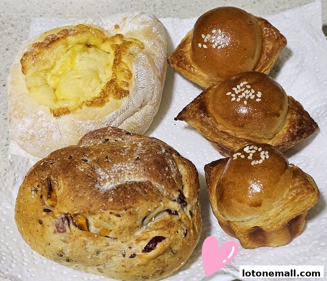 A variety of freshly baked breads and pastries are displayed on white paper towels.