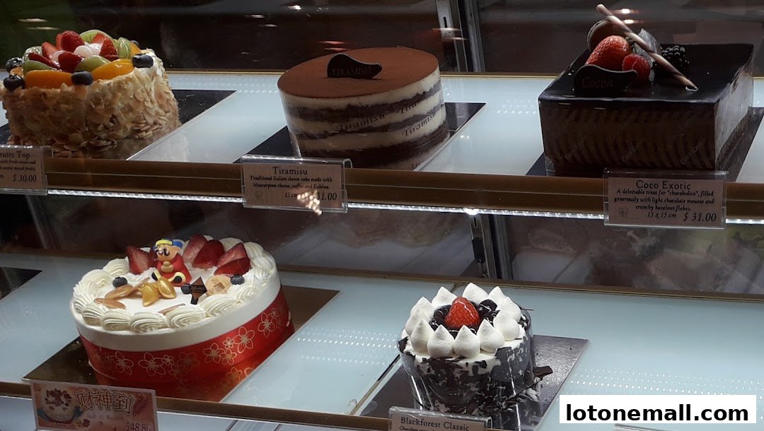 A display of various beautifully decorated cakes in a bakery's refrigerated case.
