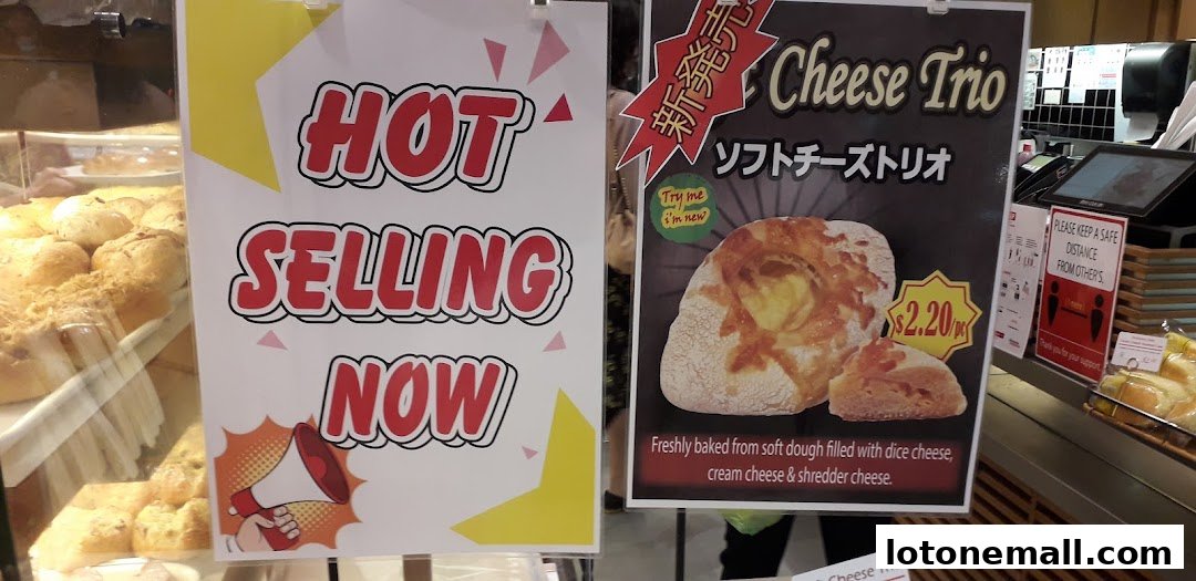 Signs advertising hot selling items and a new cheese trio pastry at a bakery.