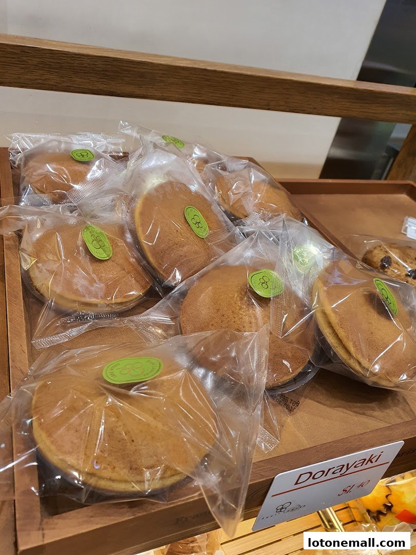 Individually packaged Dorayaki pastries displayed in a wooden tray at a bakery.