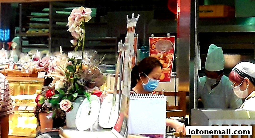 Staff members working behind the counter at a bakery with floral decorations.