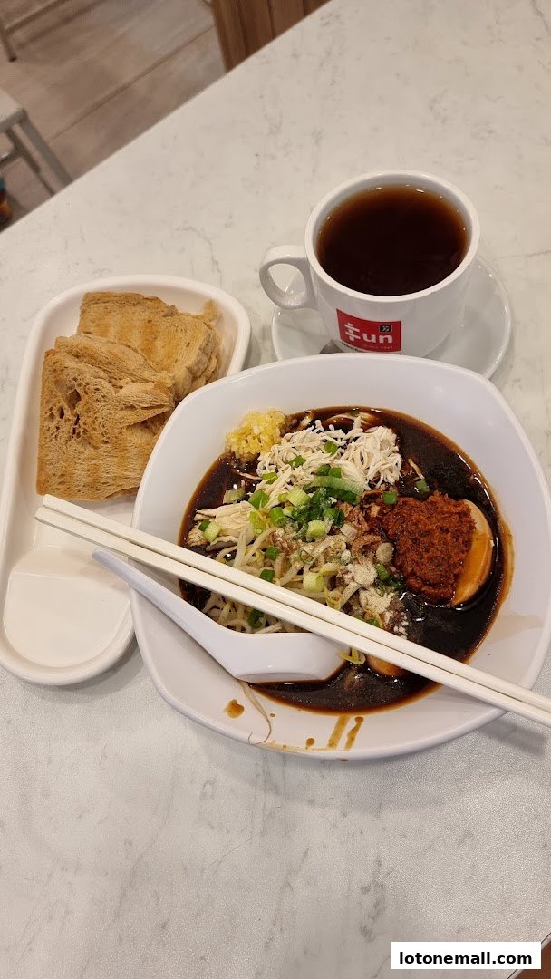A bowl of noodles with chicken, sprouts, and chili paste, served with toast and a cup of tea.