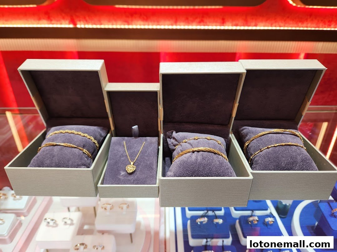 Gold jewelry, including necklaces and bracelets, displayed in open boxes inside a jewelry store.
