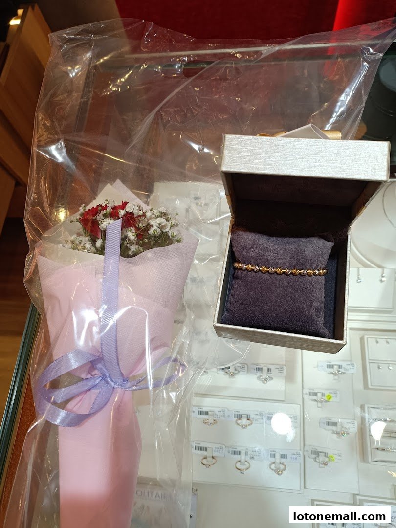 A jewelry display featuring a bracelet in a box and a small bouquet.