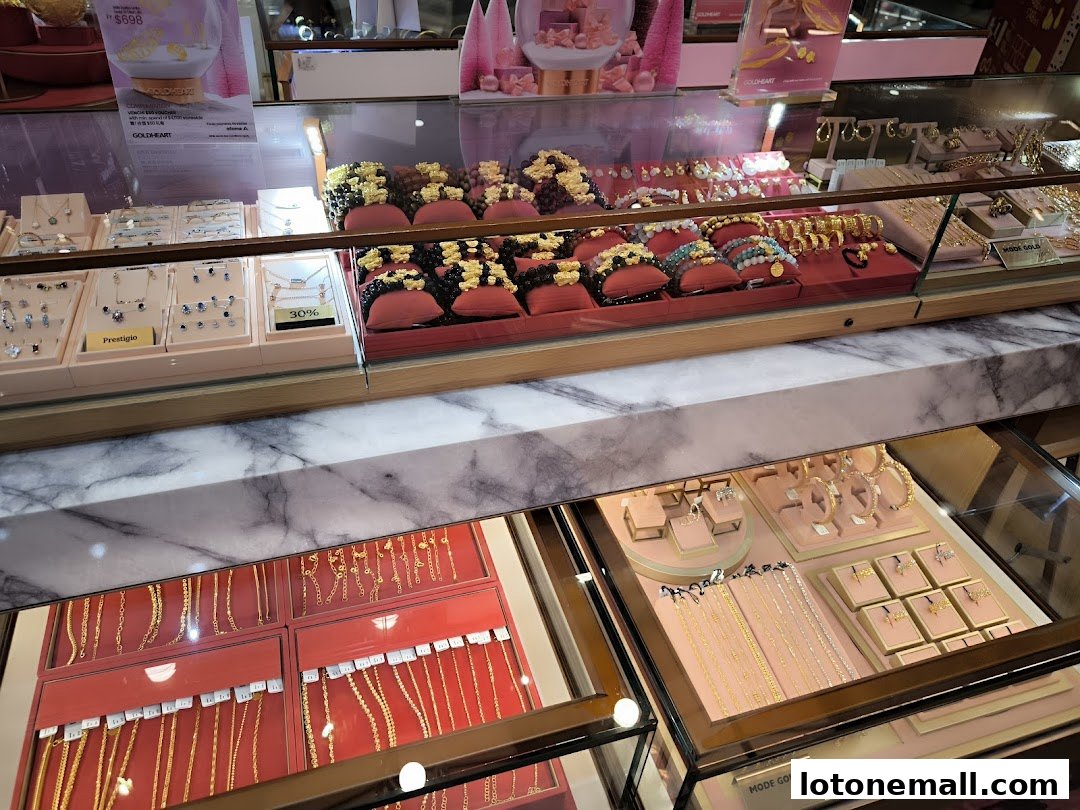 A display case filled with various gold necklaces, bracelets, and earrings from Goldheart Jewelry.