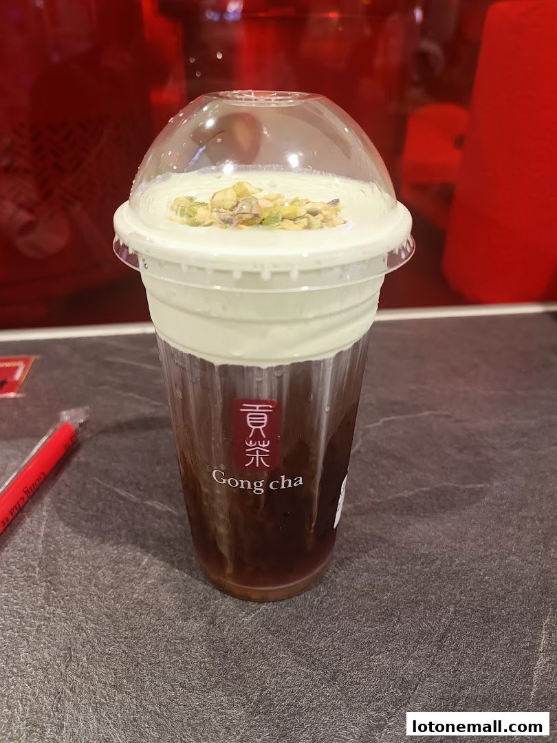 A close-up of a Gong Cha drink with a creamy topping and pistachios.