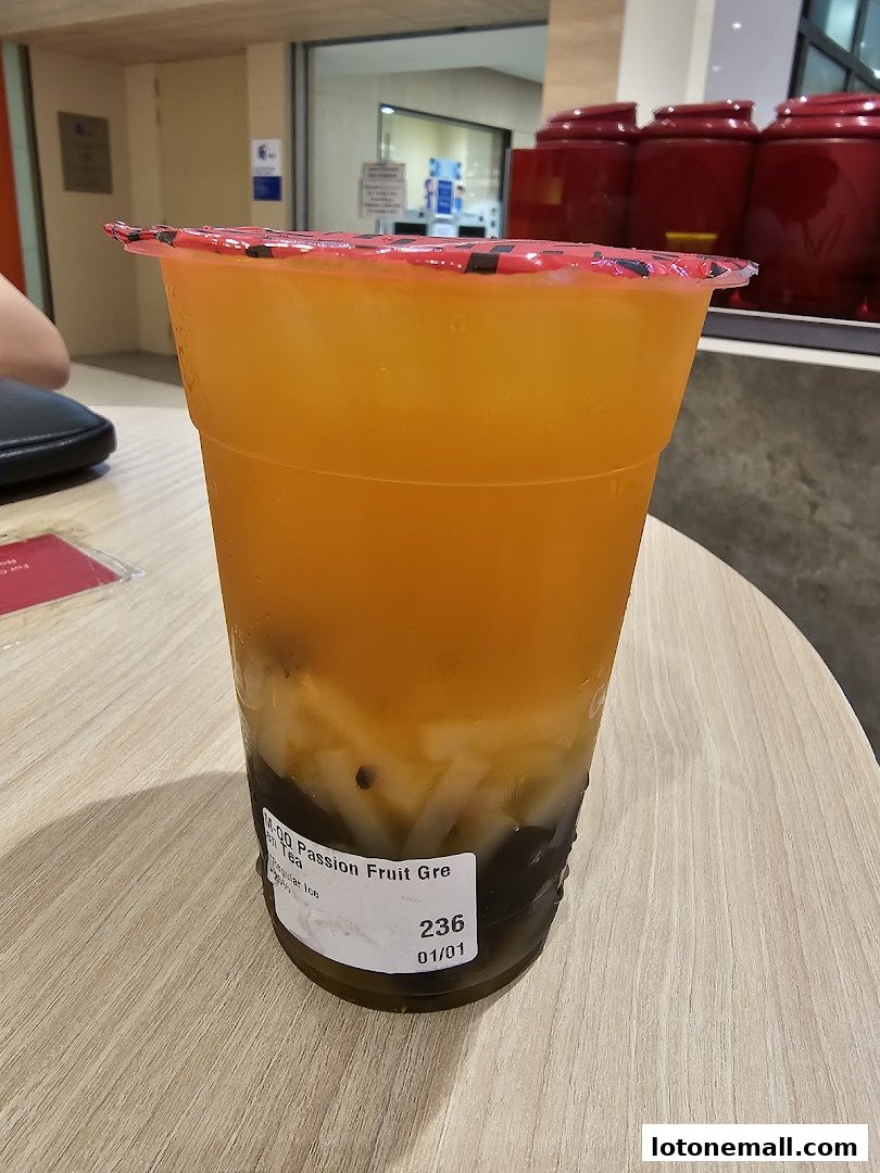 A refreshing Gong Cha passion fruit green tea with toppings on a wooden table.