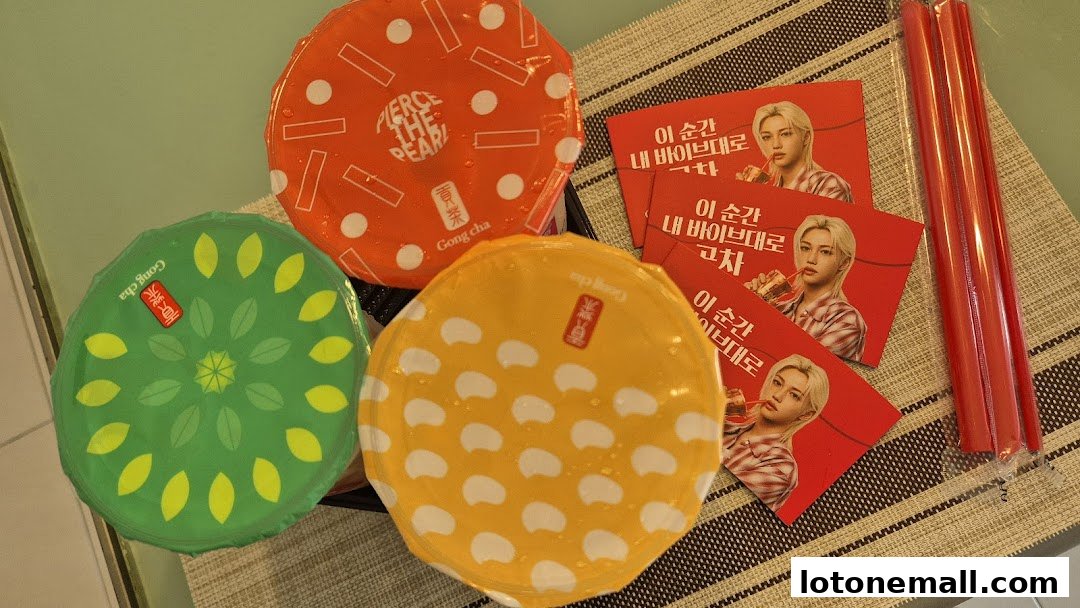 Three colorful Gong Cha bubble tea drinks with promotional cards and red straws.