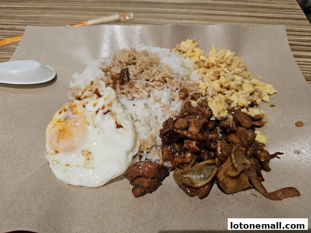 A plate of Hainanese curry rice with fried egg, scrambled egg, and chicken.