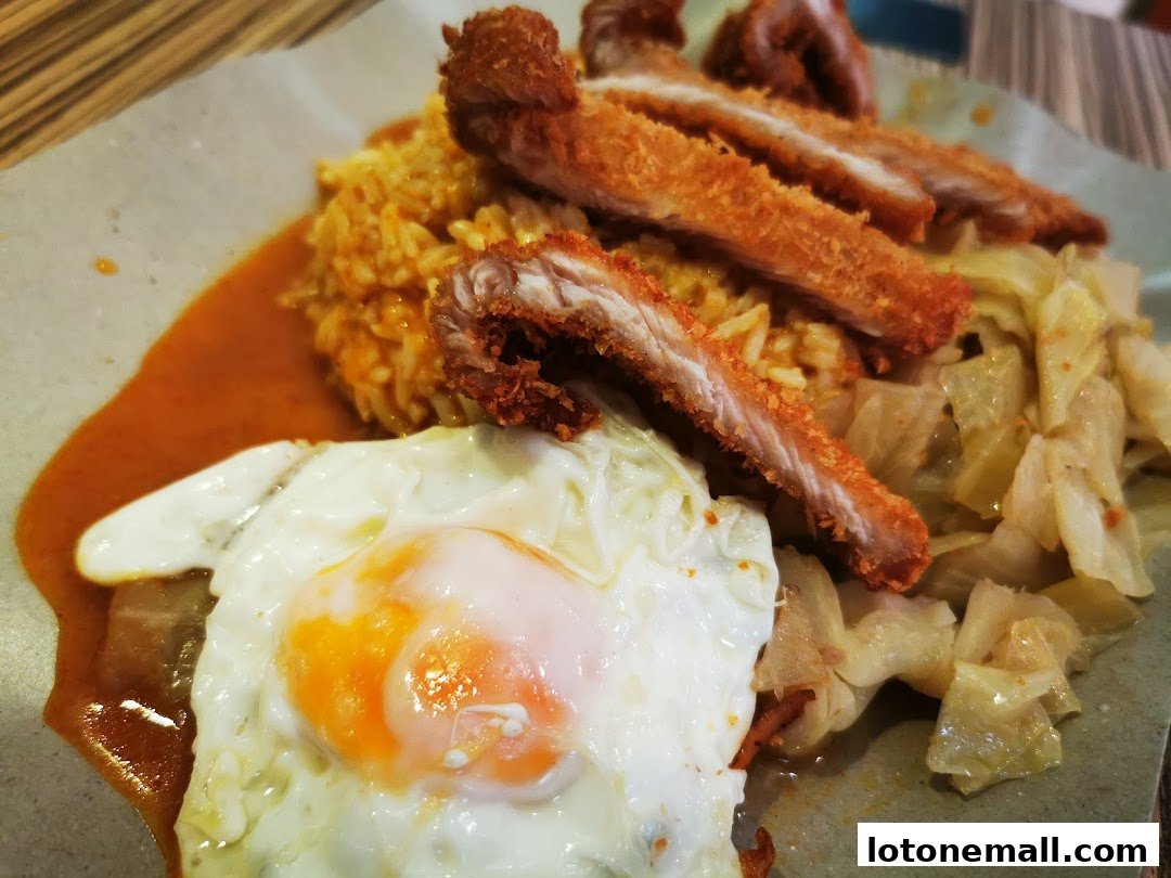 A close-up of Hainanese curry rice with fried chicken, a sunny-side-up egg, and cabbage.