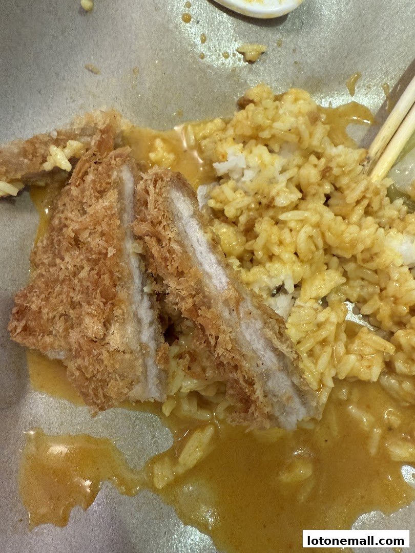 A close-up of Hainanese curry rice with crispy fried pork and fluffy rice.
