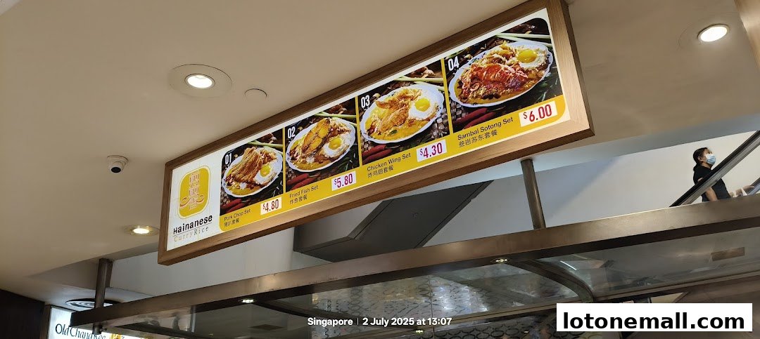 A brightly lit menu board showcasing four Hainanese curry rice sets with prices.