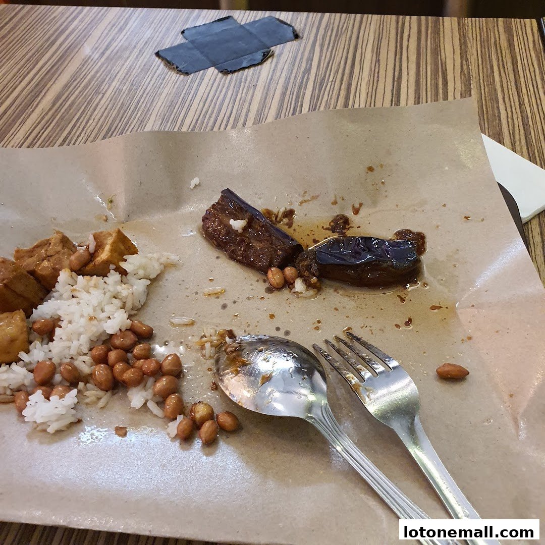 A plate of Hainanese curry rice with fried tofu, peanuts, and eggplant, partially eaten.