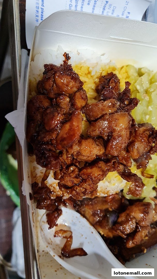 A close-up of a takeaway container filled with Hainanese curry rice and tender chicken.